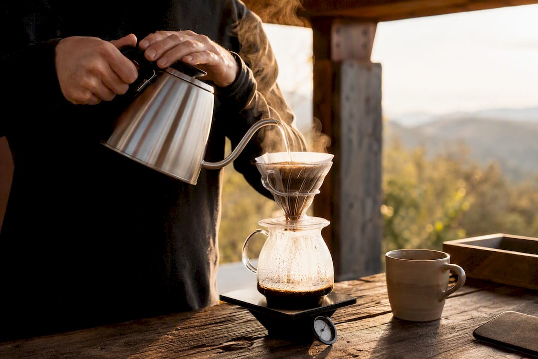 Hands pouring water over V60 coffee grounds
