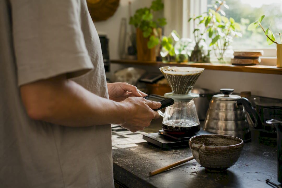 Hands measuring V60 coffee drawdown time