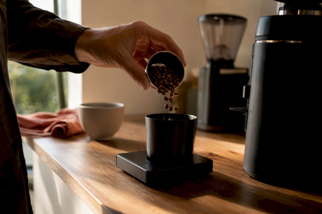 Home barista weighing beans beside coffee grinder
