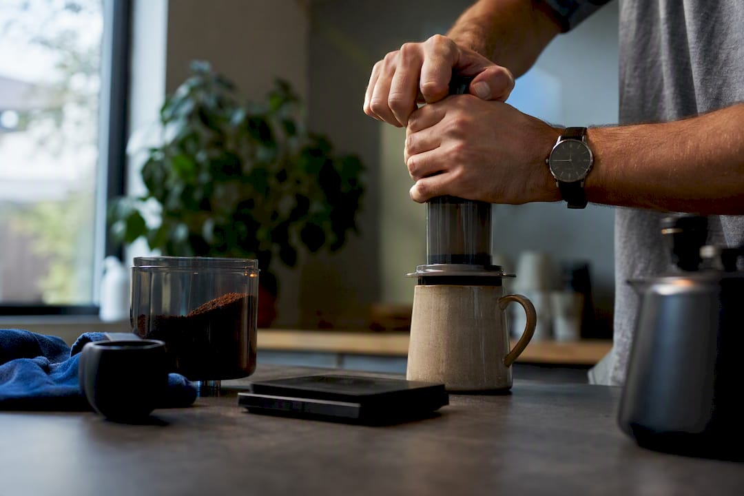 Hands pressing coffee in AeroPress brewer